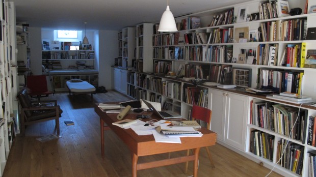 Image of the inside of a room filled with literature and a writing desk