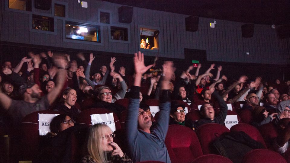Image of the audience inside SVA Theatre waving their hands