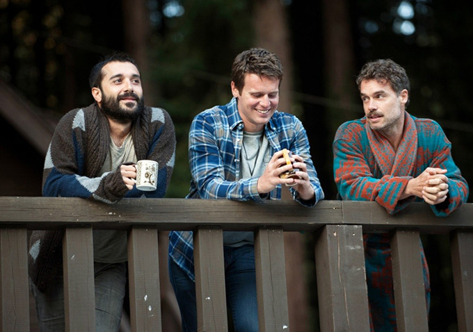 Image of three men talking on a balcony
