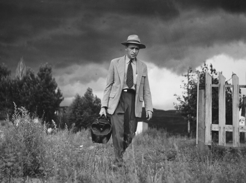 Black and white image of a man walking in a field
