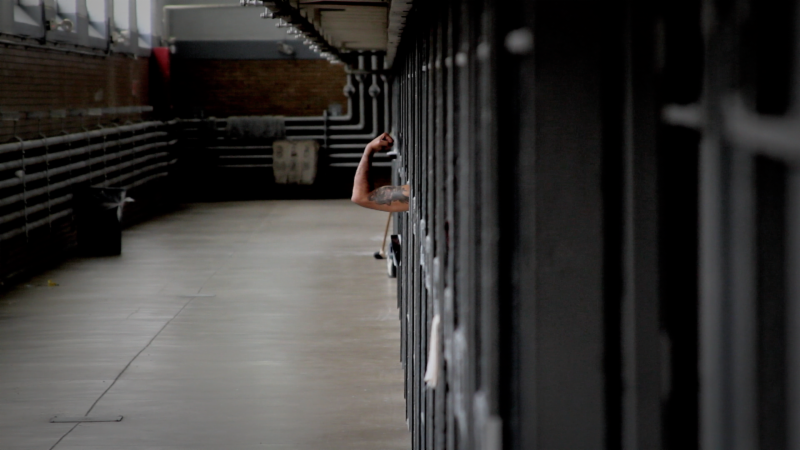 Image of prison block with an arm sticking out of the cell