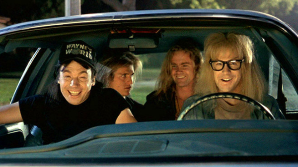 Film still from "Wayne's World". Mike Meyers, Dana Carvey, and two others are in a car smiling.