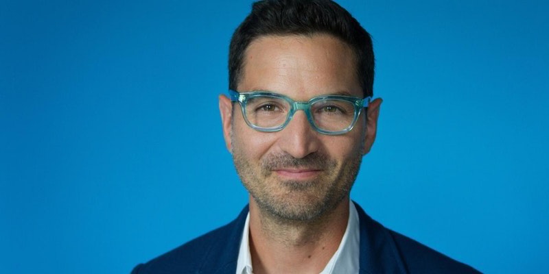 Middle aged man in clear rimmed glasses and a stubbly beard