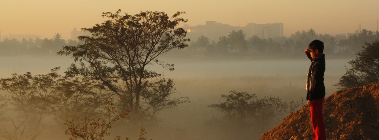 Young Asian child standing on a hill looking out onto a foggy forest