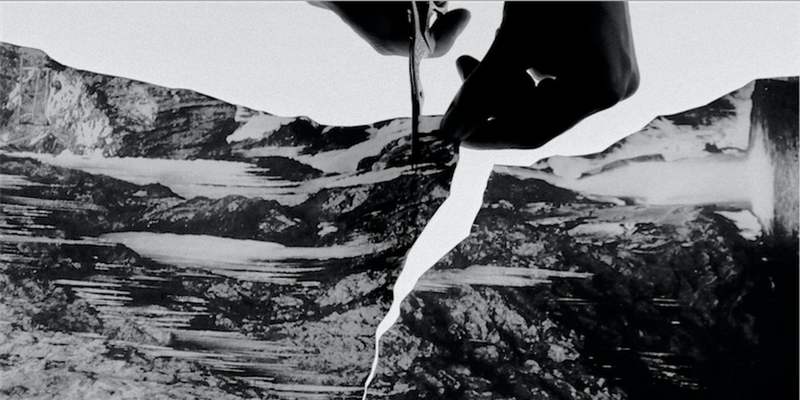 Black and white photo of hands holding scissors cutting a piece of paper