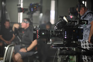Image on a film set. In the foreground, a camera sits on a tripod