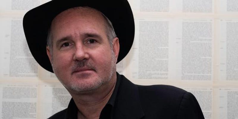 White man with stubble wearing a black cowboy hat