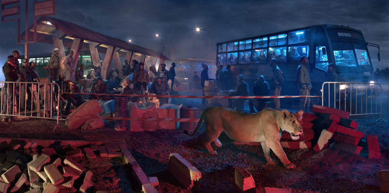 In the foreground, a lioness paces around a construction site. In the background, a bus station with many African men both waiting under a structure and on the bus itself