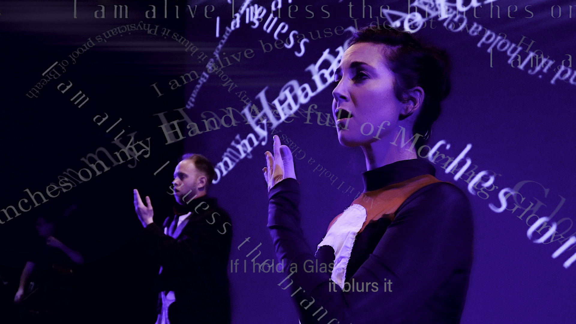 Image of a man and woman singing. Across the image are digitally imposed words that seem to spell out a part of a poem