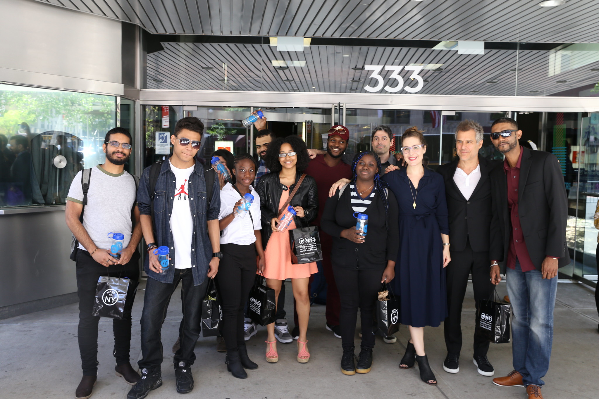 High school students standing outside SVA Theatre, displaying blue water bottles in their hands.