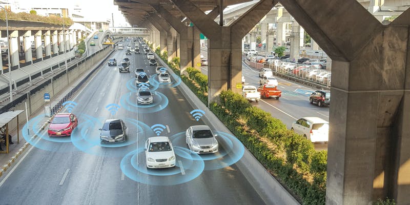 Image of cars driving down the roadway. Each car is surrounded by a blue wifi signal