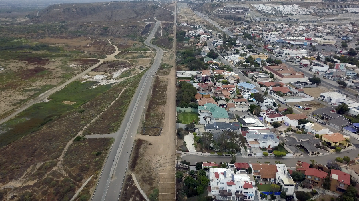 Overhead image of town with houses and buildings on the right and open land and roads to the left