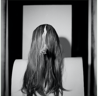 Image of a woman with long hair covering her face and several lit matches coming out of her hair