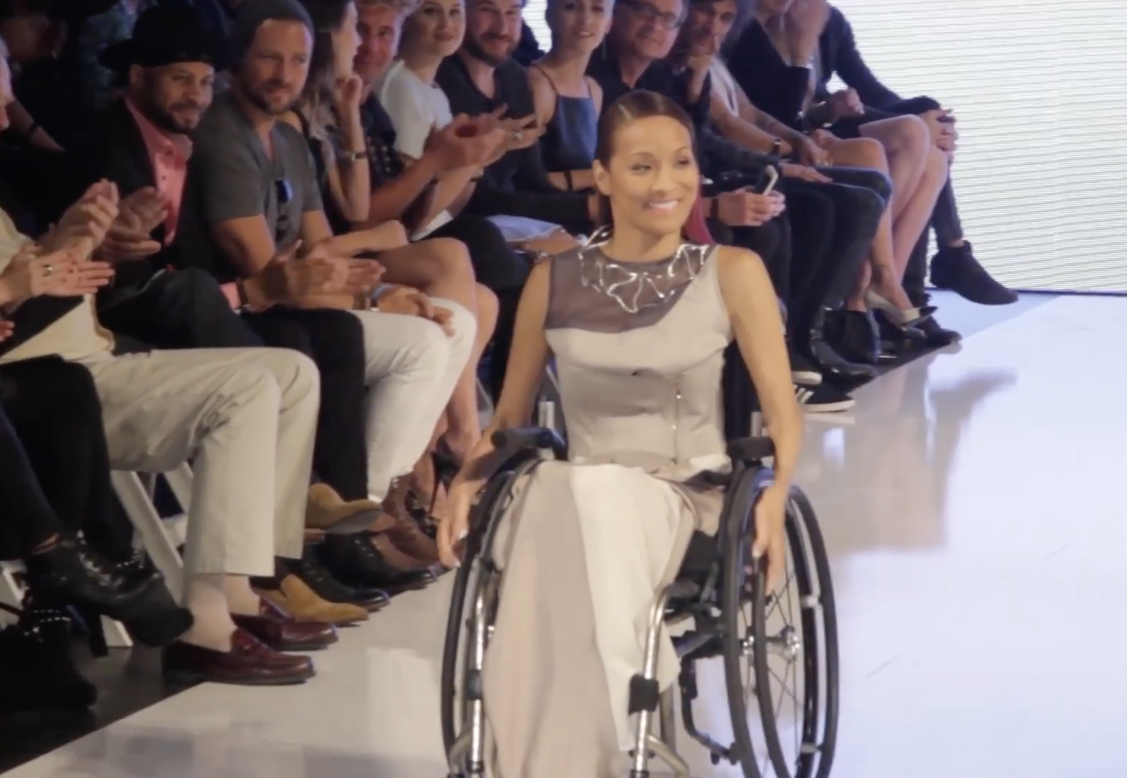 Woman in wheelchair saunters down a fashion runway